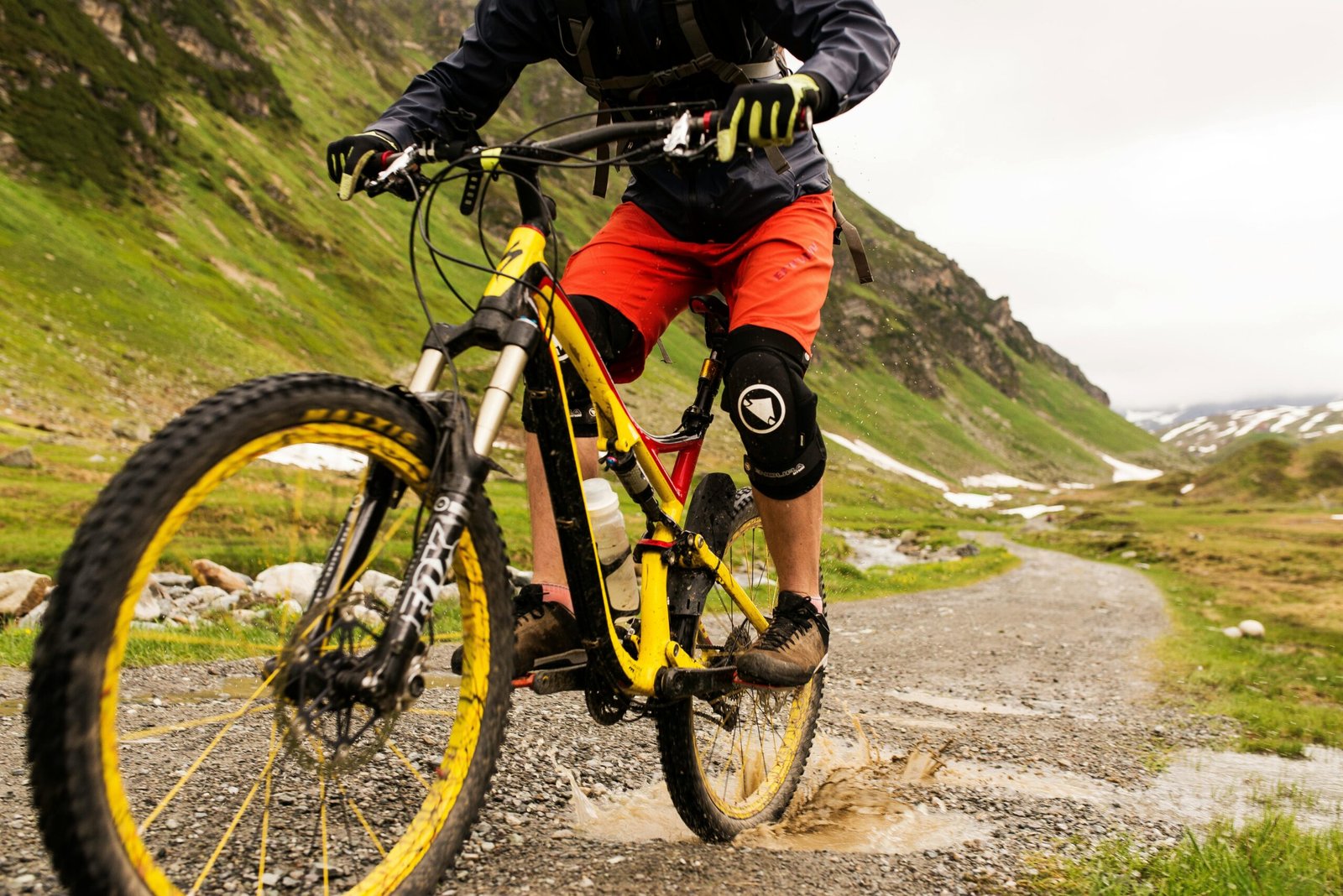 Mountain biker navigating a muddy trail through a scenic mountain landscape, showcasing outdoor adventure.